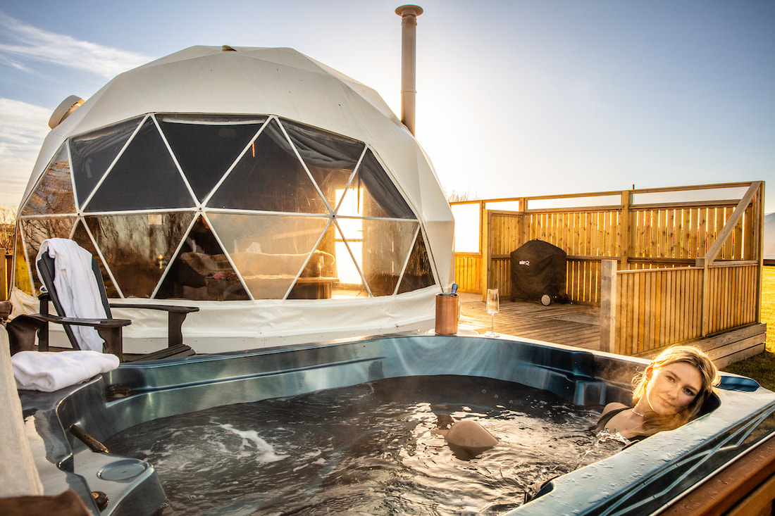 Guest relaxing in a private hot tub beside a dome